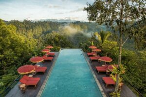 A scenic view of Bali's tropical beach at sunset with palm trees, turquoise waters, and tourists relaxing ideal for Bali holidays 2025