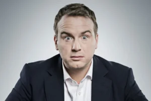 Matt Forde performing political stand-up comedy on stage