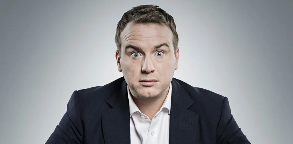Matt Forde performing political stand-up comedy on stage