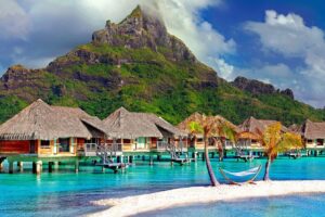Aerial view of over‑water bungalows and turquoise lagoon at sunset in Bora Bora, French Polynesia