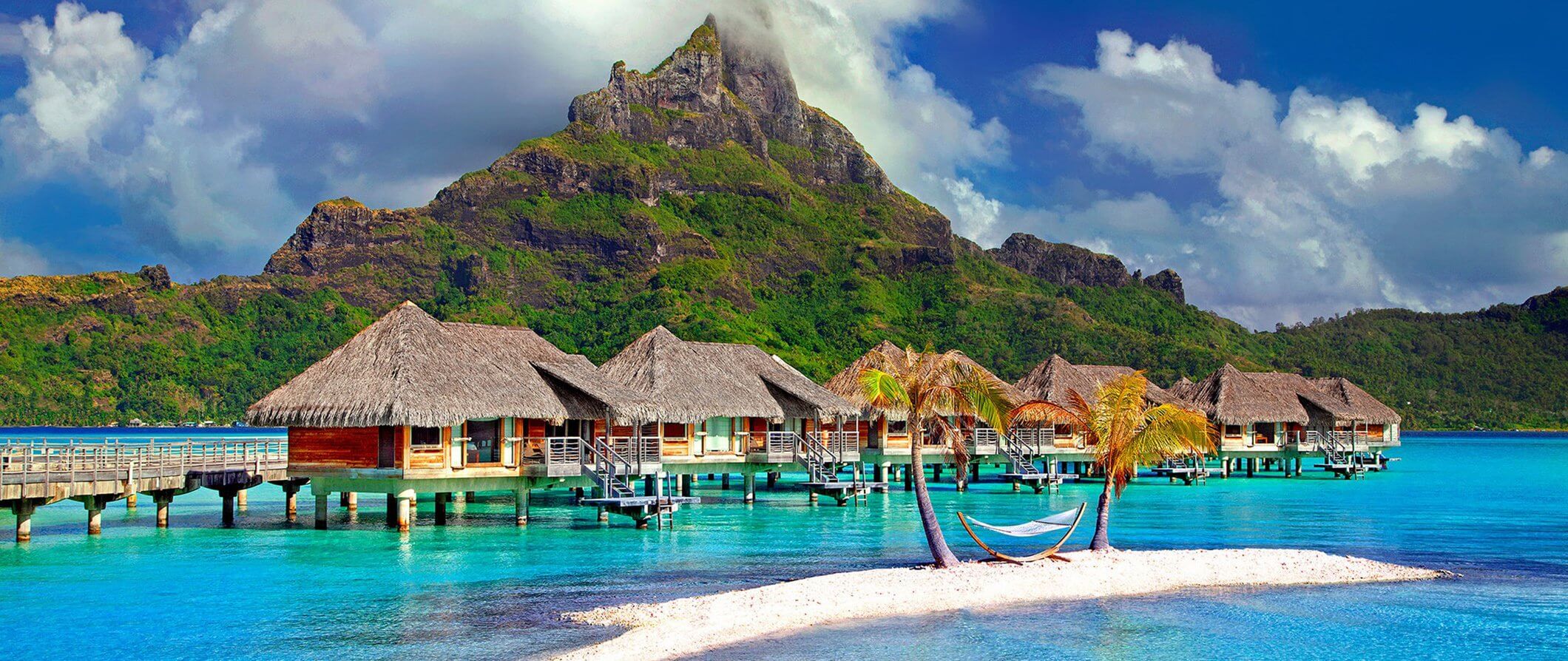 Aerial view of over‑water bungalows and turquoise lagoon at sunset in Bora Bora, French Polynesia